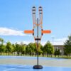 Orange and black pickleball training target with mesh netting, on a black stand, for skill practice on a court.