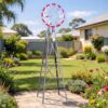 Gray metal garden windmill with red-tipped blades, rain gauge, and thermometer for outdoor decor.