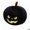 Black plush pumpkin pillow with embroidered yellow jack-o'-lantern face, brown stem, for Halloween decor.