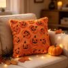 Orange plush Halloween throw pillow with raised pumpkin faces for festive home decor.