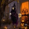Hanging lighted witch decoration, black hat, purple/black fabric dress, holding broom, for Halloween outdoor decor.