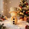 Woven Rattan Snowman Lantern With Top Hat, Black Buttons, And Gold Ribbon, Glowing Warmly For Christmas Decor.