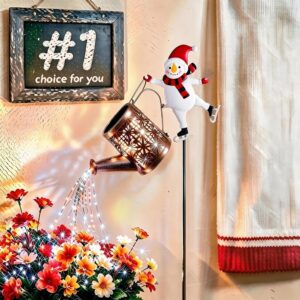 Bronze metal watering can with snowflake cutouts and LED lights, held by a white snowman figure for garden decor.