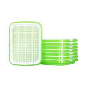 Stackable green and white plastic seed sprouting trays with perforated mesh, for growing microgreens indoors.
