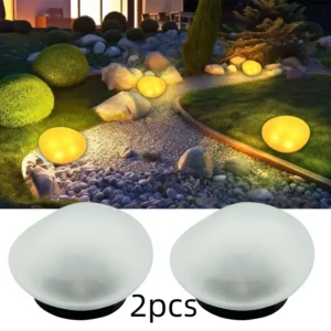 2pcs white frosted plastic pebble-shaped solar garden lights, illuminating a gravel path at night.
