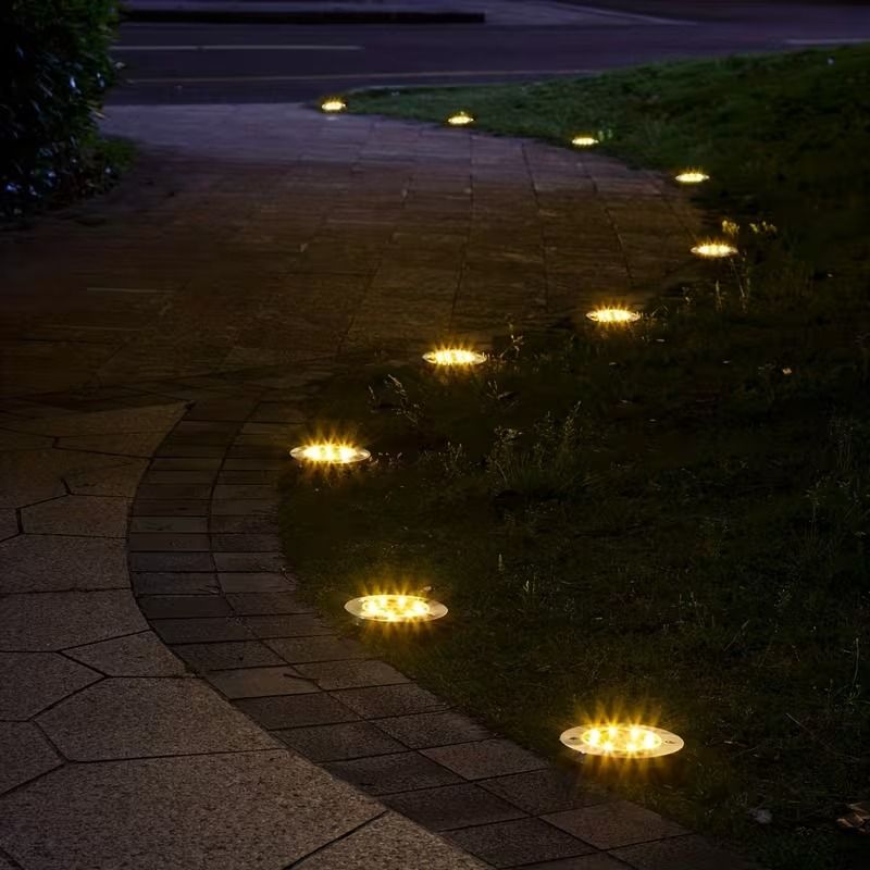 8-Pack Solar Garden Lights | Waterproof Outdoor Lighting – Sumo Deals Round, Silver Metal Solar Ground Lights With Warm Yellow Leds Illuminating A Garden Path At Night.
