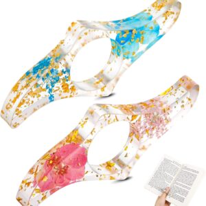 2 clear resin thumb book page holders with dried flowers (blue, pink) and gold flakes for comfortable reading.