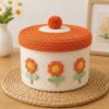 Handmade cotton rope storage basket with orange lid, pompom, and embroidered flowers for home decor.