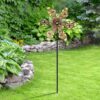 Metal butterfly wind spinner, green and brown, with six butterfly-shaped blades on a black stake for garden decor.