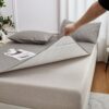 Gray quilted polyester mattress protector, reversible with white underside, for bed comfort and protection.
