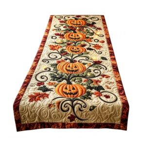 Quilted Halloween table runner, beige with orange jack-o'-lanterns, fall leaves, and black scroll embroidery. Festive de