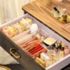 Clear acrylic drawer organizers with multiple compartments for makeup, brushes, and accessories.