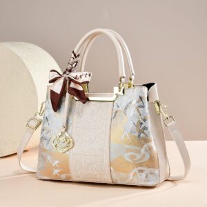 Elegant cream faux leather handbag with gold/silver floral embroidery, brown ribbon, and shoulder strap for daily use.