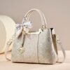 Elegant beige faux leather handbag with intricate floral embroidery, gold hardware, and silk scarf accent for women.