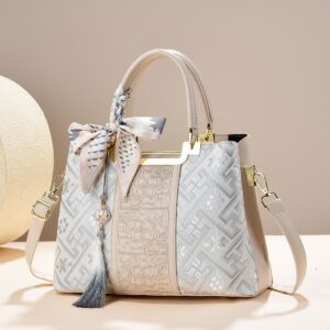 Beige faux leather handbag with embroidered geometric and floral patterns, silk scarf, and tassel charm for women.