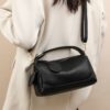 Black pebbled leather shoulder bag with top handle, gold hardware, and zipper closure for everyday use.