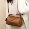 Brown pebbled leather shoulder bag with top handle, zipper closure, and gold hardware for daily use.