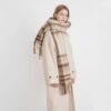 Cozy brown plaid fringed wool scarf for women, worn over a beige coat for winter fashion.