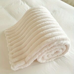 Rolled Cream Ribbed Plush Fleece Blanket For Cozy Warmth On A Bed Or Sofa.