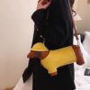 Dachshund dog-shaped shoulder bag, brown and yellow patent leather, with a yellow hat, for novelty fashion.